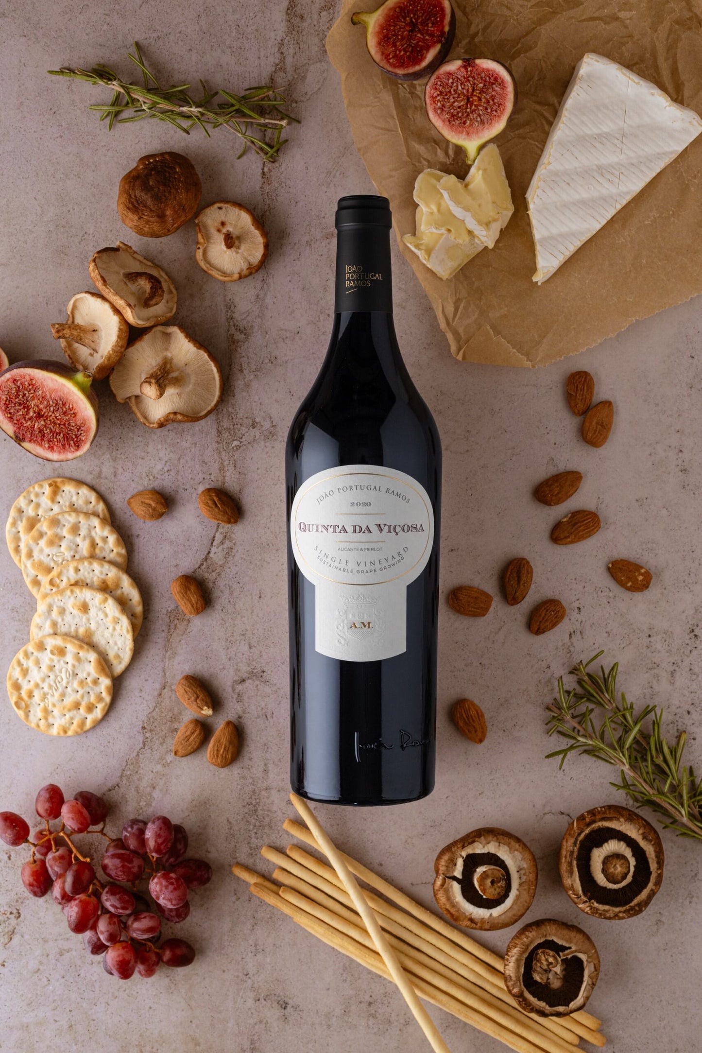 Quinta da Viçosa Single Vineyard 2020, surrounded by figs, cheese, crackers, almonds, mushrooms, and herbs, exuding elegance.