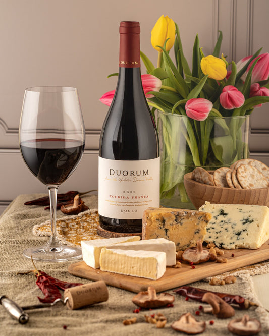 Duorum Touriga Franca red wine with a glass, cheese, crackers, mushrooms, and tulips in the background.