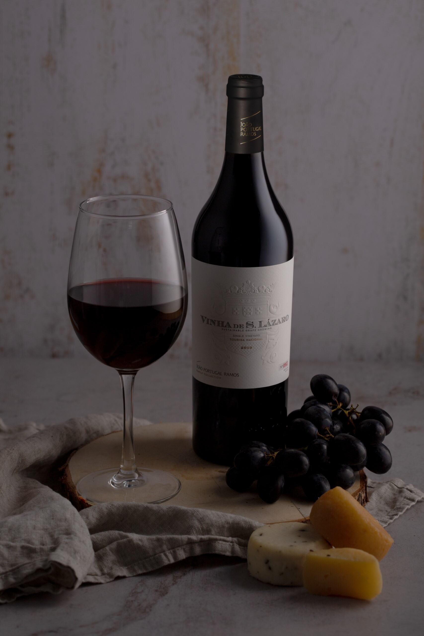 Red Wine: Vinha de São Lázaro — Single Vineyard (2021), a glass of wine, black grapes, and assorted cheeses.