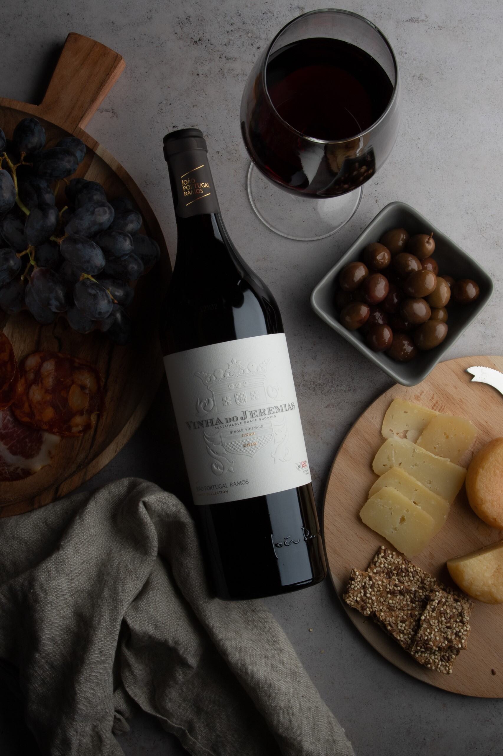 Vinha do Jeremias Single Vineyard red wine, elegantly placed with cheese, olives, grapes, charcuterie, and a glass of wine.